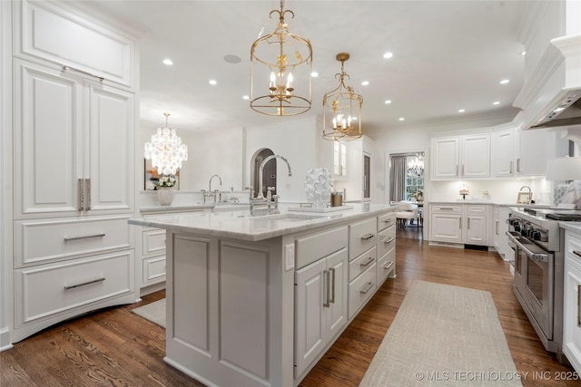 kitchen with a sink, white cabinets, a notable chandelier, and range with two ovens