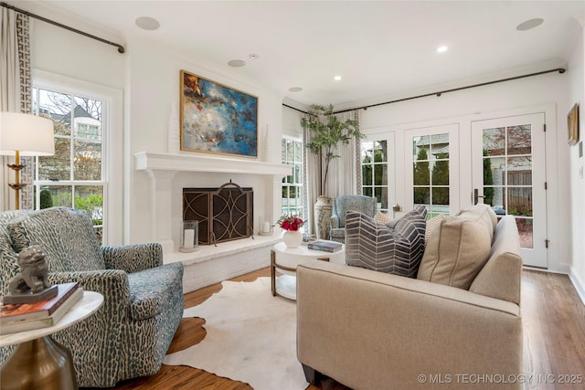living room with a fireplace with raised hearth, recessed lighting, a wealth of natural light, and wood finished floors