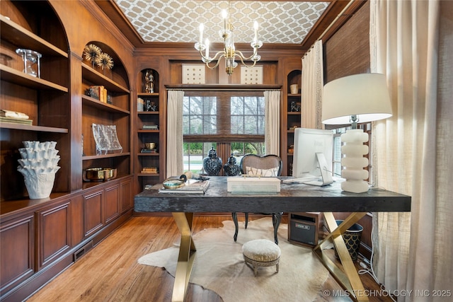 office with crown molding, light wood-type flooring, built in shelves, and an inviting chandelier