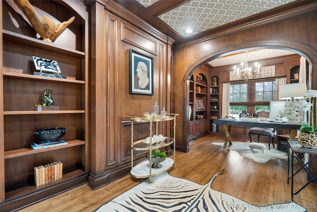 office featuring an inviting chandelier, arched walkways, ornamental molding, and built in shelves