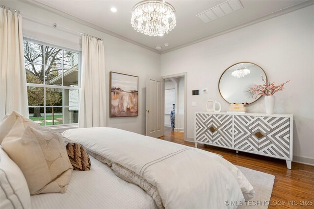 bedroom featuring crown molding, a notable chandelier, baseboards, wood finished floors, and visible vents