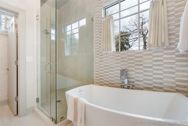 bathroom featuring a stall shower, a freestanding bath, a wealth of natural light, and tile patterned floors