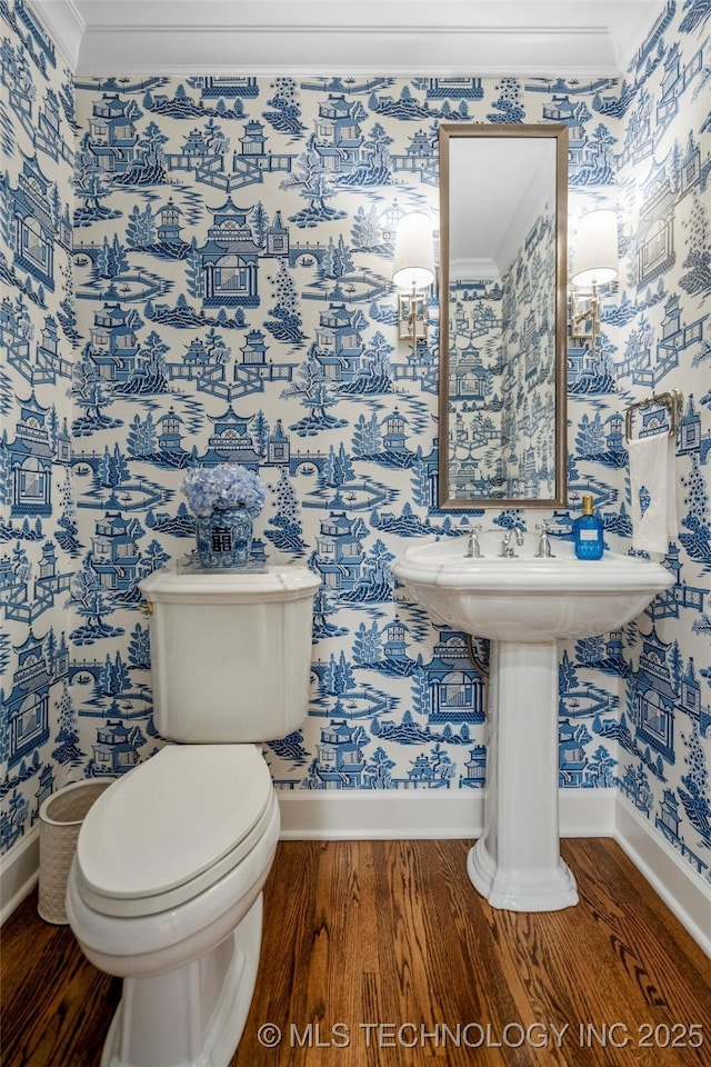 bathroom featuring crown molding, wood finished floors, toilet, baseboards, and wallpapered walls