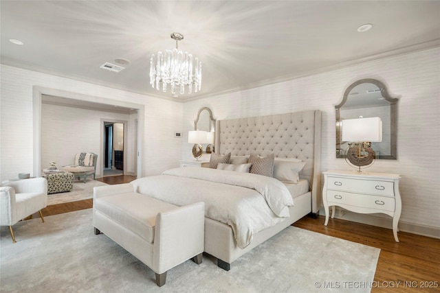 bedroom with visible vents, ornamental molding, wood finished floors, and a chandelier