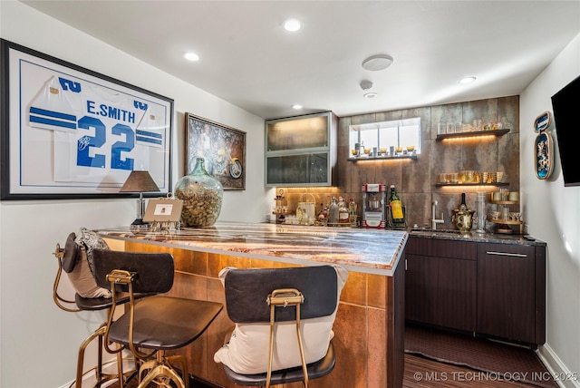 bar with wood finished floors, recessed lighting, tasteful backsplash, a sink, and wet bar