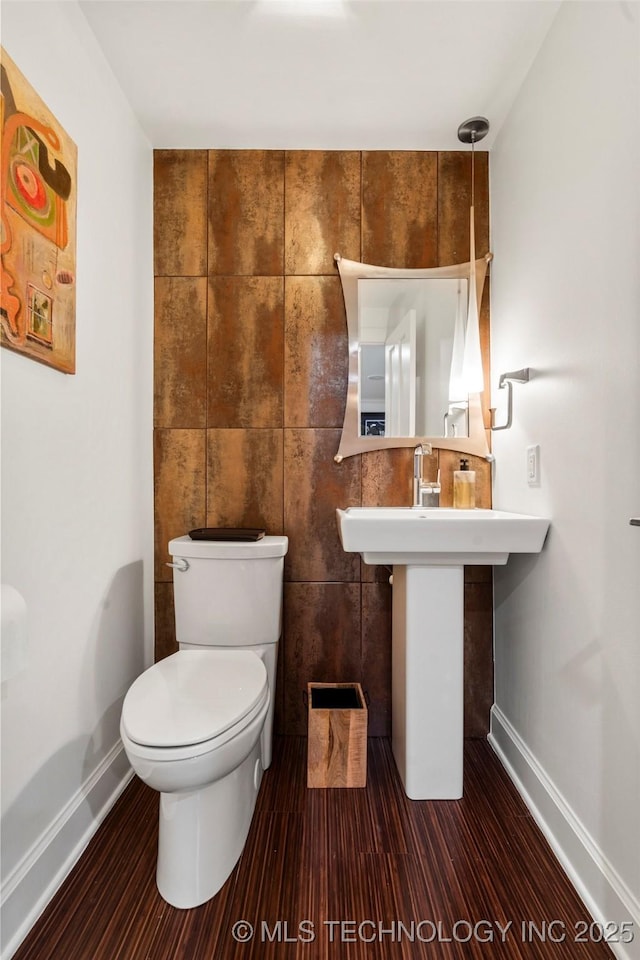 bathroom featuring toilet, baseboards, and tile walls