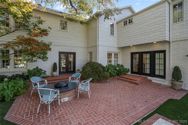 back of house with french doors, a fire pit, a patio area, and brick siding