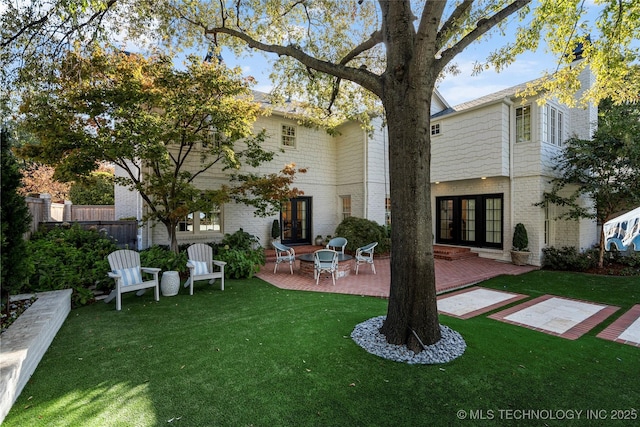 rear view of property with brick siding, a patio area, a yard, and french doors