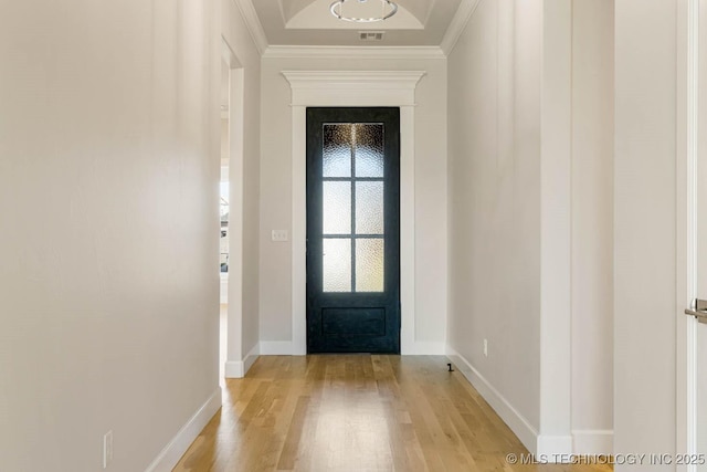 doorway with crown molding, light wood finished floors, and baseboards