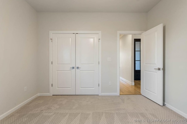 unfurnished bedroom with baseboards, a closet, and light carpet