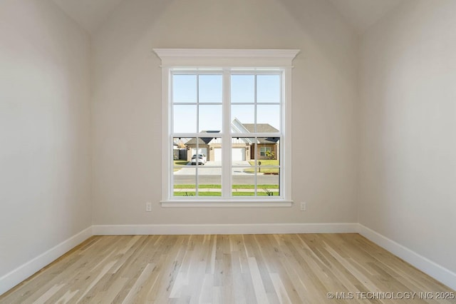 unfurnished room with baseboards, lofted ceiling, and light wood-style floors