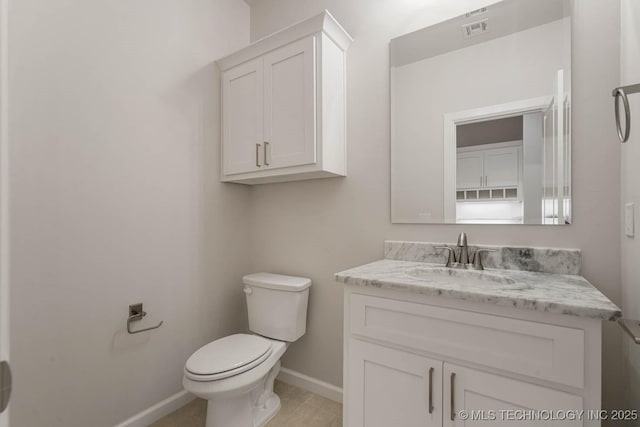 half bathroom with tile patterned flooring, visible vents, vanity, toilet, and baseboards