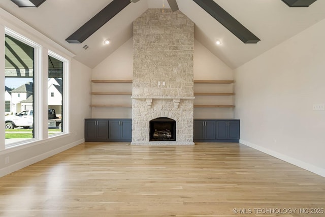 unfurnished living room with beamed ceiling, high vaulted ceiling, and light wood-style flooring