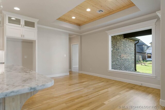 interior space featuring a tray ceiling, ornamental molding, wood ceiling, and light wood-style floors