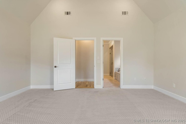 unfurnished bedroom featuring high vaulted ceiling, visible vents, and light carpet