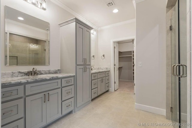 full bath featuring a sink, a shower stall, a spacious closet, visible vents, and ornamental molding