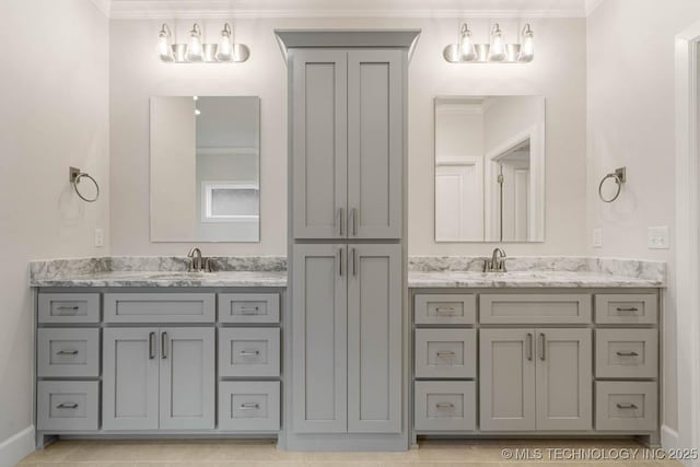 bathroom with crown molding, two vanities, and a sink