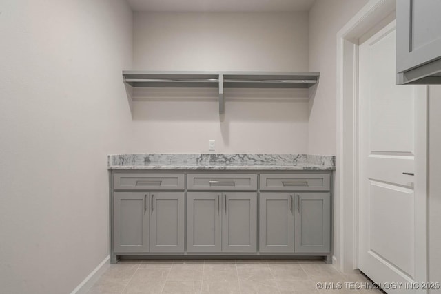 clothes washing area featuring baseboards and light tile patterned floors