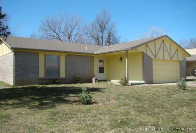 view of front facade with brick siding, a garage, and a front yard