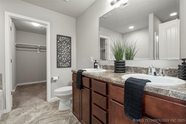 full bathroom with double vanity, a walk in closet, visible vents, and a sink