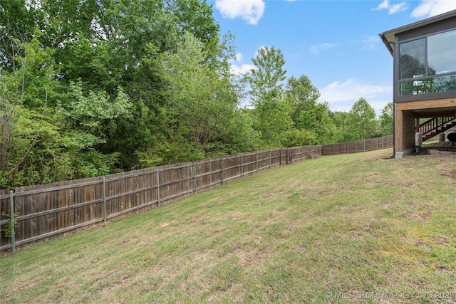 view of yard with a sunroom, a fenced backyard, and stairway