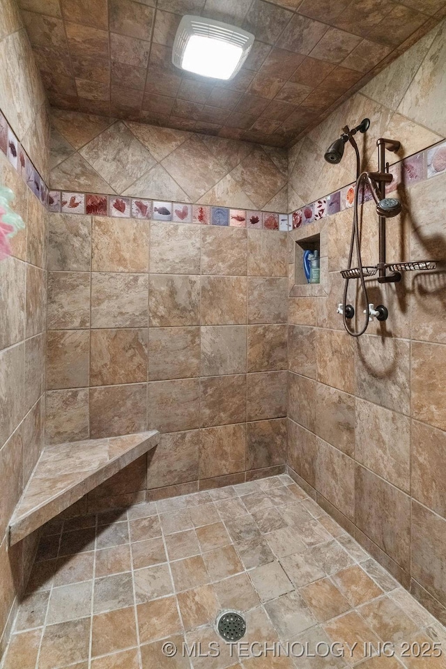full bath with stone finish floor and tiled shower