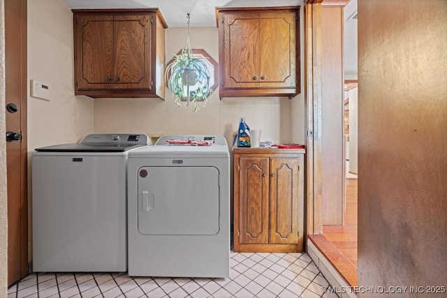 laundry room with cabinet space, light tile patterned floors, and washer and dryer