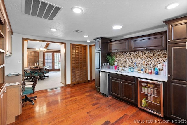 bar with visible vents, refrigerator, beverage cooler, wet bar, and a notable chandelier