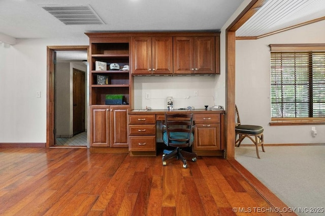 office space featuring visible vents, baseboards, built in desk, and dark wood finished floors