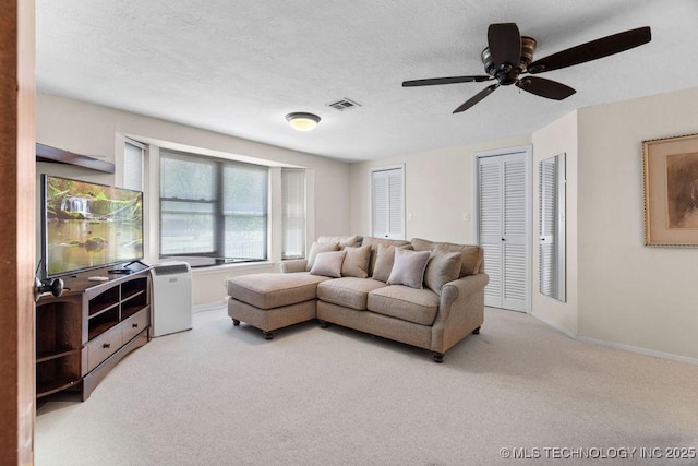 living room featuring carpet floors, ceiling fan, baseboards, and visible vents