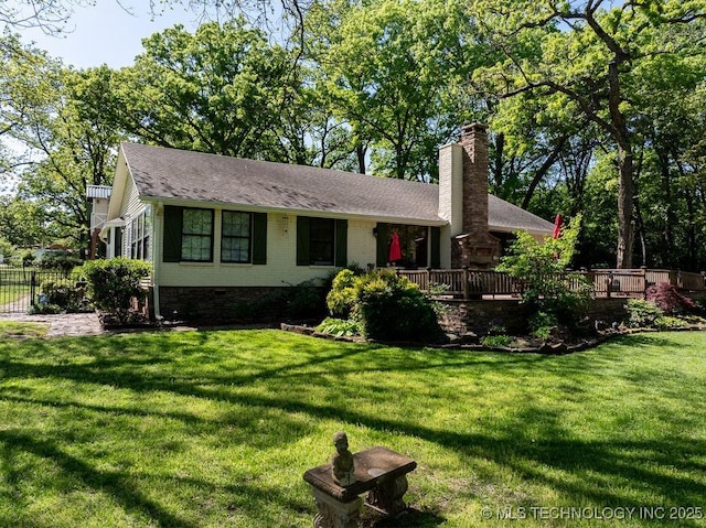 single story home with roof with shingles, a wooden deck, a chimney, and a front lawn