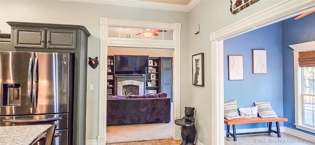 kitchen featuring baseboards, ceiling fan, a fireplace, and stainless steel fridge with ice dispenser