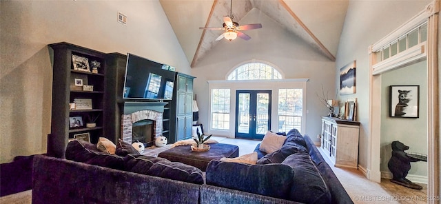living area featuring a ceiling fan, visible vents, a brick fireplace, high vaulted ceiling, and light carpet