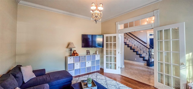 living room with crown molding, a chandelier, french doors, wood finished floors, and stairway