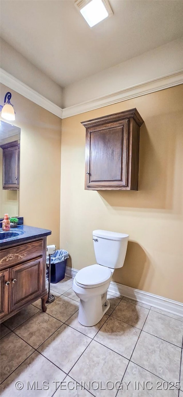 bathroom with baseboards, tile patterned floors, vanity, toilet, and ornamental molding