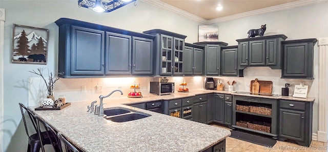 kitchen with crown molding, a peninsula, glass insert cabinets, stainless steel microwave, and a sink
