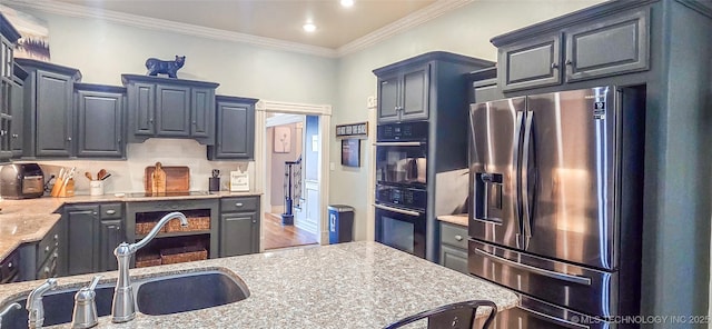 kitchen featuring crown molding, dobule oven black, stainless steel fridge, light countertops, and a sink