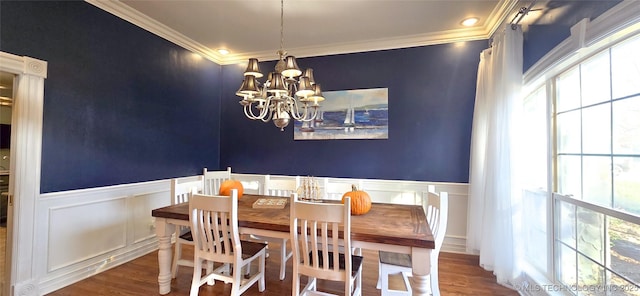 dining area with an inviting chandelier, ornamental molding, wood finished floors, and a decorative wall