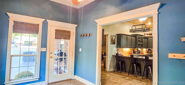 doorway to outside featuring baseboards and a ceiling fan