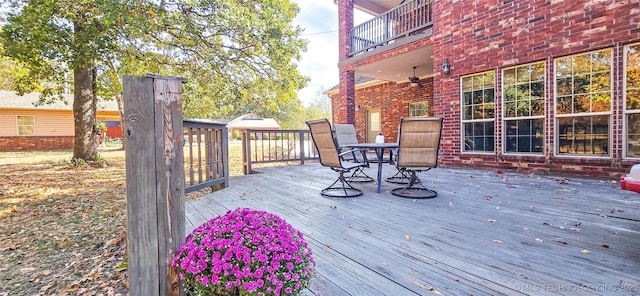 wooden terrace with outdoor dining space and ceiling fan