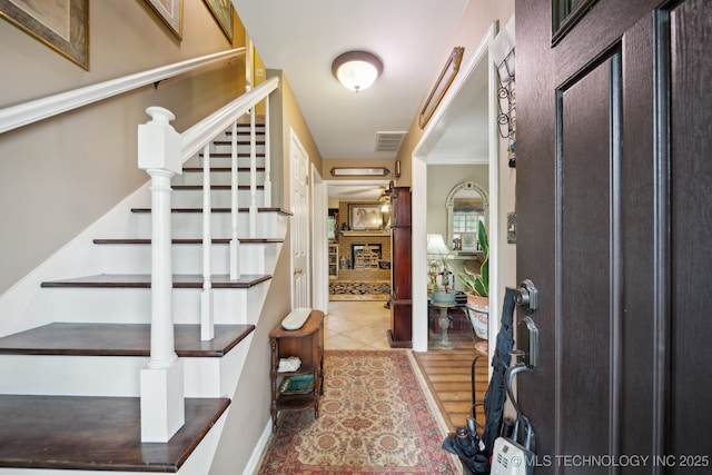 tiled entrance foyer featuring visible vents and stairway