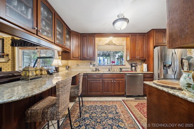 kitchen featuring light stone counters, tasteful backsplash, stainless steel appliances, and light tile patterned flooring