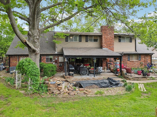 back of house with a lawn, a chimney, a patio area, and brick siding