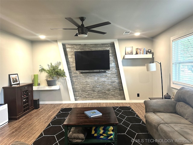 living room with baseboards, ceiling fan, wood finished floors, and visible vents