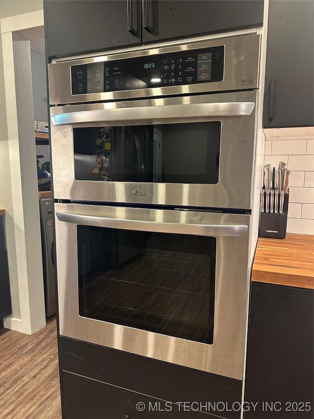 details with stainless steel double oven, wood counters, and wood finished floors