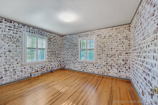 3428 S Birmingham Ave, Tulsa, OK 74105 - spare room featuring visible vents, baseboards, wood finished floors, and brick wall