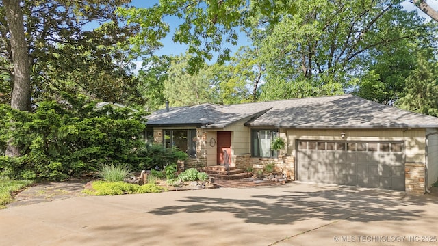 3428 S Birmingham Ave, Tulsa, OK 74105 - view of front facade with a garage, roof with shingles, driveway, and stone siding