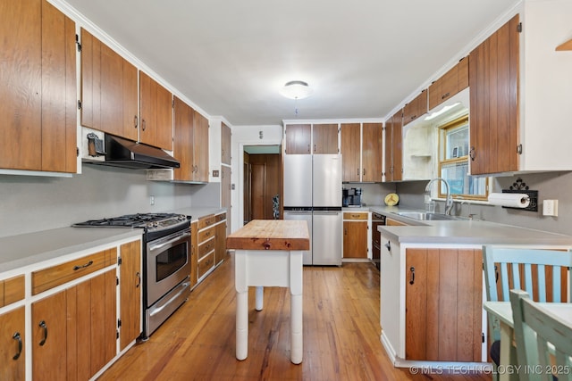 3428 S Birmingham Ave, Tulsa, OK 74105 - kitchen featuring a sink, brown cabinetry, stainless steel appliances, light wood-type flooring, and under cabinet range hood