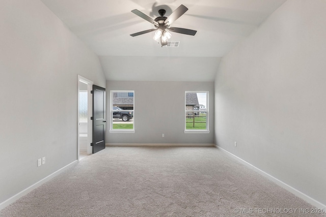 spare room featuring ceiling fan, visible vents, vaulted ceiling, baseboards, and light carpet