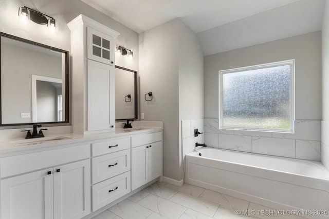 bathroom with a sink, a garden tub, double vanity, and marble finish floor